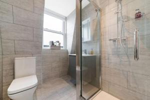 a bathroom with a toilet and a glass shower at Stunning Double Rooms within a Loft space in London