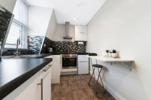 a kitchen with white cabinets and a counter top at Stunning Double Rooms within a Loft space in London