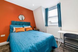 a bedroom with a blue bed and an orange wall at Stunning Double Rooms within a Loft space in London