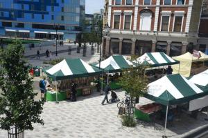 a market with green and white tents in a city street at 4 Bed Apartment- Archway Station in London