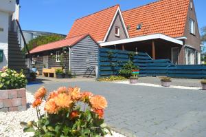 una casa con una cerca azul y algunas flores en Vakantiehuisje Te Gast op Texel, en Den Burg