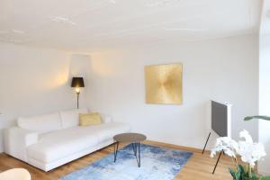 a white living room with a white couch and a table at The R Apartment Cholfirst in Schaffhausen