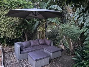 a purple couch and an umbrella on a deck at New Lynn Self- Contained Unit near Golf Course in Auckland