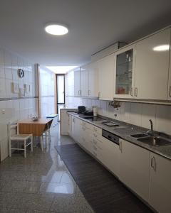 eine Küche mit weißen Schränken und einem Tisch darin in der Unterkunft Casa da Senra in Vila do Conde