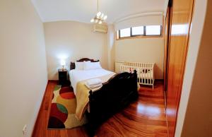ein Schlafzimmer mit einem Bett und einem Kinderbett in der Unterkunft Casa da Senra in Vila do Conde