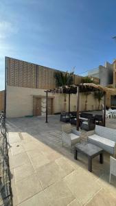 a patio with benches and tables in front of a building at درة العروس فيلا فاخره بمسبح داخلي in Durat Alarous