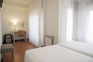 a bedroom with a bed and a desk with a chair at Hotel Delta in Tudela