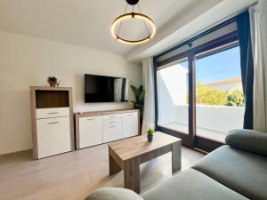 a living room with a couch and a tv and a window at Perseo by Albir Proper Properties in Albir