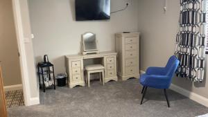 a room with a dresser with a mirror and a blue chair at Johnny Murphy's Guest Rooms in Meigh