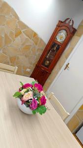 a vase of flowers on a table with a clock at Il Rifugio di Piazza dell' Oca in Ronciglione