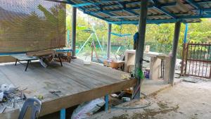 a porch with a wooden deck with a blue roof at Teratak Cikgu Homestay in Pasir Puteh