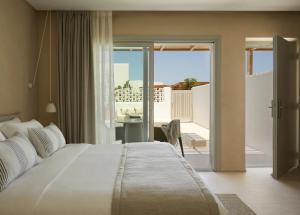 a bedroom with a large white bed and a balcony at PAROCKS Luxury Hotel & Spa in Ambelas