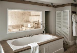 a white bath tub in a bathroom with a mirror at The Cozy Hotel & Lofts Timmendorfer Strand in Timmendorfer Strand