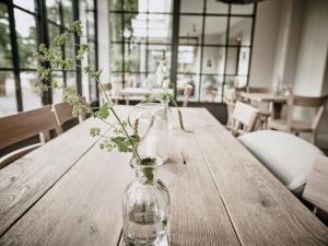 a vase with flowers sitting on a wooden table at The Cozy Hotel & Lofts Timmendorfer Strand in Timmendorfer Strand