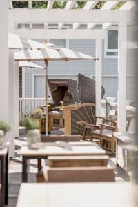 a patio with a white pergola and tables and a piano at The Cozy Hotel & Lofts Timmendorfer Strand in Timmendorfer Strand