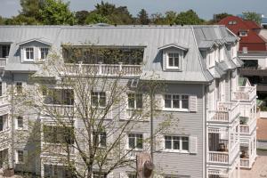 ein großes weißes Gebäude mit grauem Dach in der Unterkunft The Cozy Hotel & Lofts Timmendorfer Strand in Timmendorfer Strand