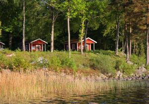 duas casas numa colina ao lado de um corpo de água em Urshult Camping em Urshult
