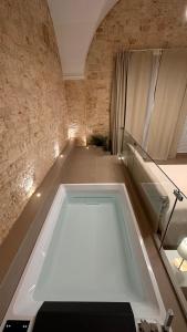 a bath tub in a room with a brick wall at Pietra Antica Luxury in Sannicandro di Bari