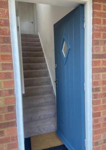 a blue door leading to a staircase with a stair case at Little Hill View in Milton Ernest
