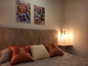 a bedroom with a bed with three paintings on the wall at Departamento dos dormitorios con cochera Tres Arroyos -3- in Tres Arroyos