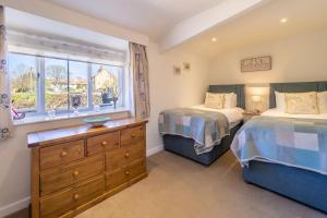 a bedroom with two beds and a window at Three Tuns Cottage in Little Walsingham