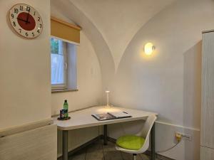 a desk with a chair and a clock on a wall at Tiny central studio apartment Tour As Ljubljana in Ljubljana