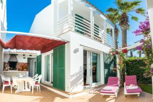 une maison avec une terrasse dotée de chaises roses et d'une table dans l'établissement Villa Blanc, à Sa Caleta