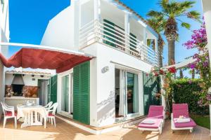 a house with a patio with pink chairs and a table at Villa Blanc in Sa Caleta