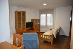 - un salon avec une télévision et une chaise dans l'établissement Aparthotel Tres Caminos, à El Grado