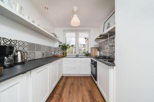 a kitchen with white cabinets and black counter tops at Close to everywhere, cosy place in Krakow
