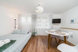 a white bedroom with a bed and a table at Close to everywhere, cosy place in Krakow