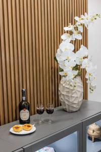 uma mesa com dois copos de vinho e um vaso com flores brancas em Boavista Executive Studios no Porto