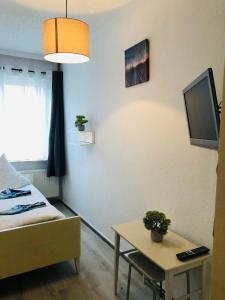 a room with a bed and a table and a tv at Haus Deitje in Borkum