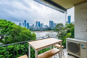 布里斯本的住宿－Riverside apartment with city & Story Bridge view，市景阳台配有桌椅。