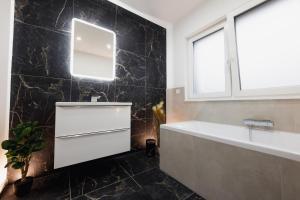 uma casa de banho com uma banheira, um lavatório e um espelho. em Luxus-Neubauvilla am Tierpark em Alsdorf