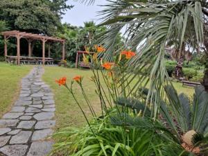 un jardín con flores naranjas y un camino de piedra en Bandi House, en Seogwipo