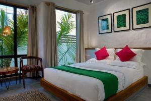 a bedroom with a large bed with red and green pillows at Hotel North House - Best Boutique Hotel in Haldwani in Haldwāni