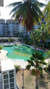 a resort swimming pool with a palm tree and a building at ROSSA HOLIDAY APARTMENT in Kuah