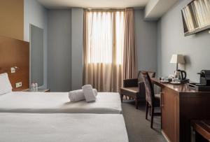 a hotel room with a bed and a desk at Hotel Madanis in Barcelona