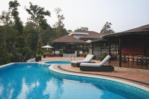 a swimming pool with two lounge chairs next to a house at Inika in Ponnampet