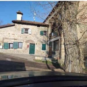 een stenen huis met een groene deur in een straat bij La corte dei celti la fonte 1 in San Benedetto Del Querceto