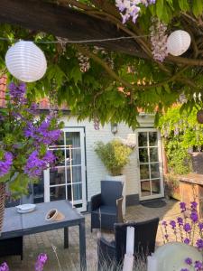 a patio with a table and purple flowers at By Mosk in Engelum