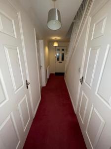 un pasillo con dos puertas y una alfombra roja en Room 2 - Chassagne Guest House, en Church Coppenhall