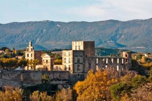 an old building on a hill with mountains in the background at Luberon Large House 4 bedrooms in La Tour-dʼAigues
