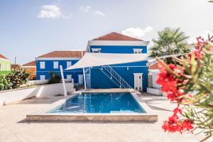 a blue house with a swimming pool and a white umbrella at The Freedom Hotel in Willemstad