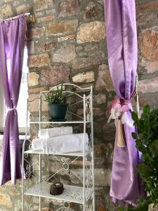 - un porte-serviettes devant un mur en pierre avec des rideaux violets dans l'établissement Masal Küçükköy Boutiquehotel, à Ayvalık