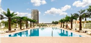 a large swimming pool with palm trees and a building at Europe Hotel & Casino All Inclusive in Sunny Beach