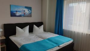 a bedroom with a bed with a blue blanket and a window at Ferienapartments Pension Elsternest in Bad Liebenwerda