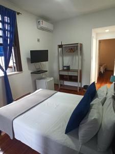 a bedroom with a large white bed with blue pillows at Pousada Estrela do Mar in Salvador