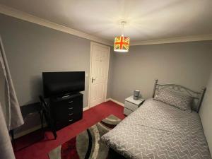 a bedroom with a bed and a flat screen tv at Room 3 - Chassagne Guest House in Church Coppenhall